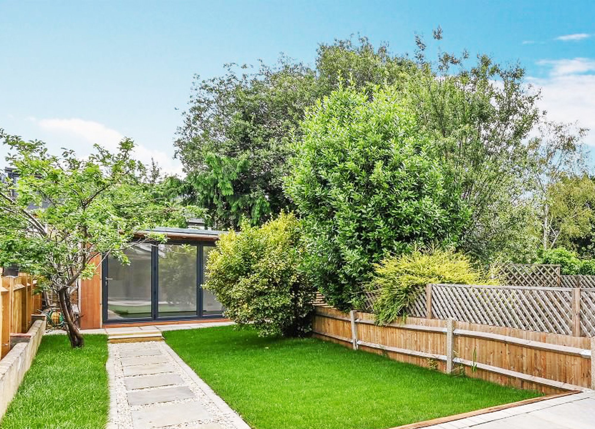 3 Door Bifold vertical wood cladded Garden Room, with pathed pathway and grass lawn