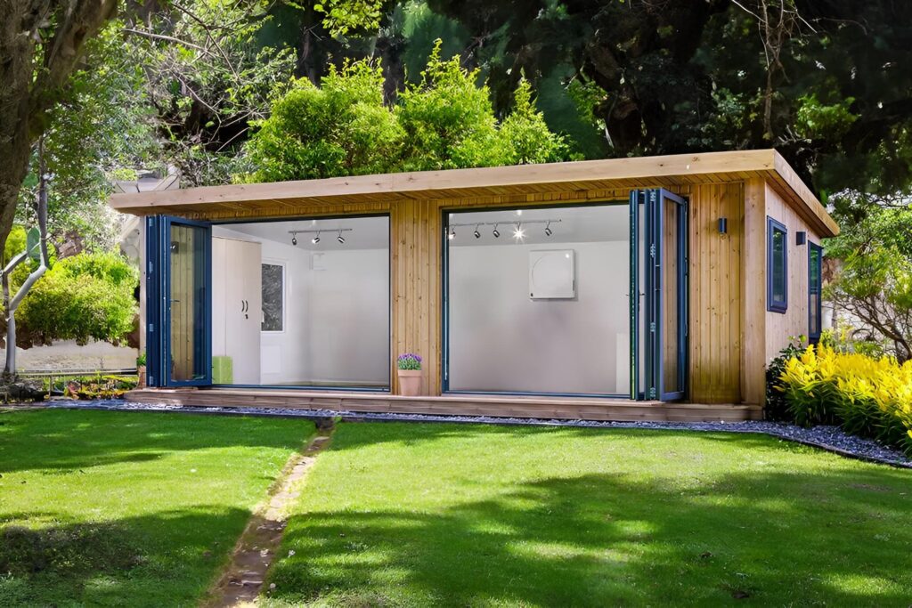 Vertical wood cladded garden room with anthracite double bifold doors, chrome internal lighting, surrounded by green garden